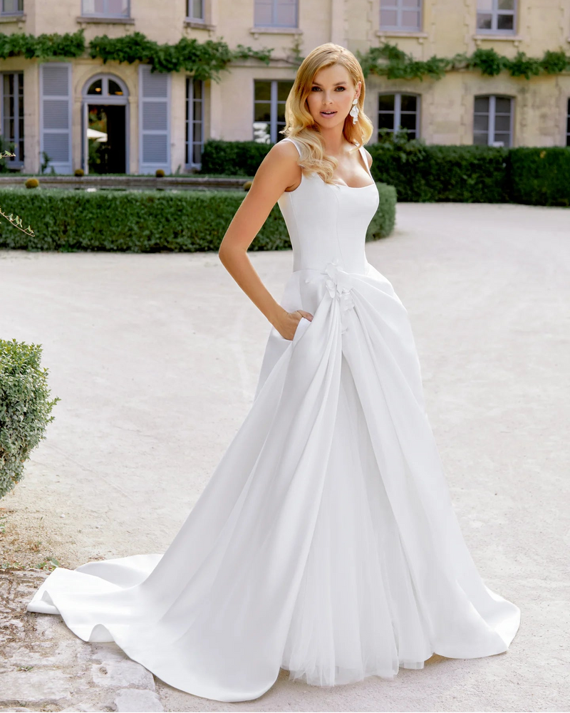 Woman in a white wedding dress standing in front of a classical building.