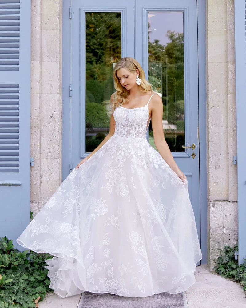 Woman in a white wedding dress standing in front of a classical building with blue shutters and an arched door.