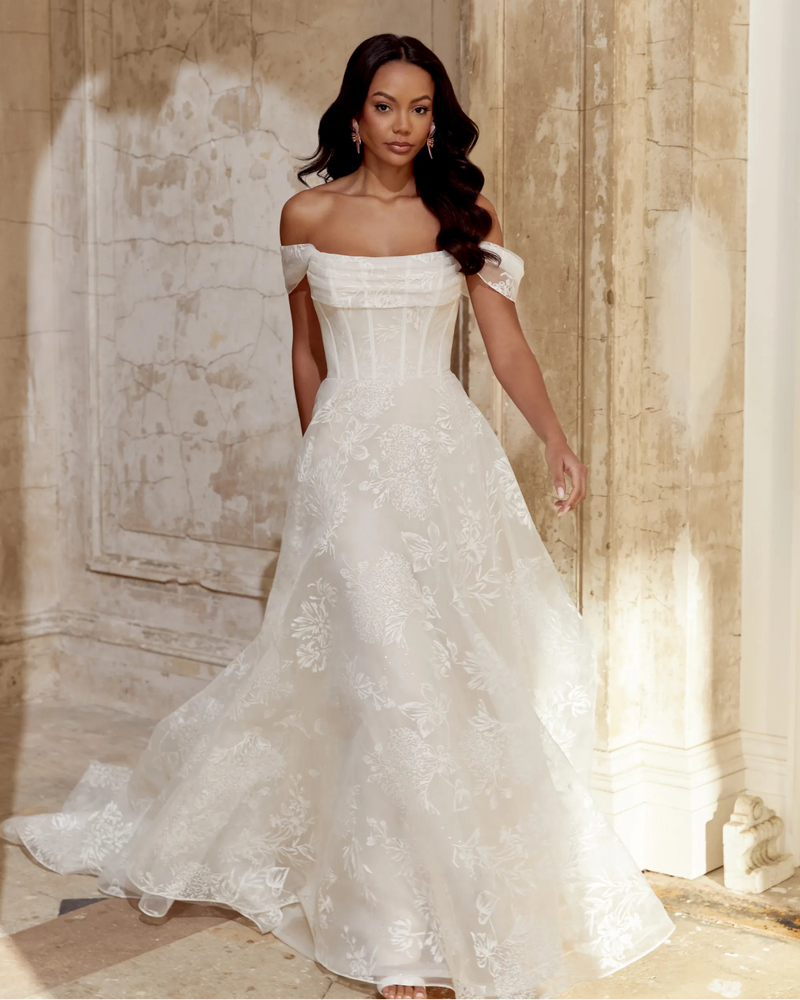 Woman in a white wedding dress standing in a grand hall with marble walls.