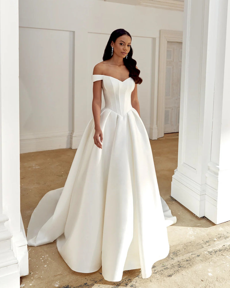Woman in a white wedding dress standing in a bright, architecturally designed room.