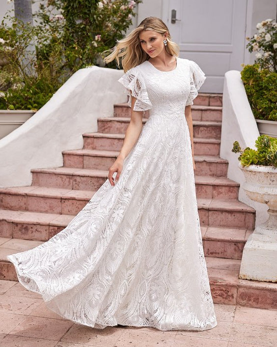 Woman in a white lace dress standing on steps outdoors