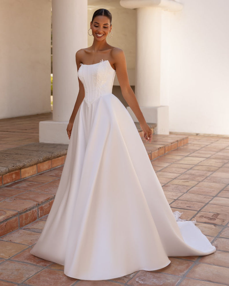Woman in a white strapless gown standing on a tiled patio.