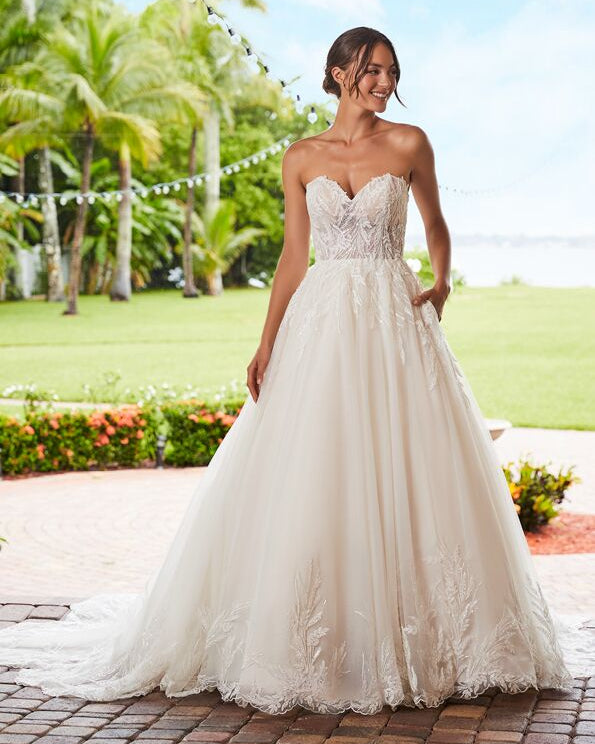Woman in a strapless wedding dress standing outdoors with palm trees in the background